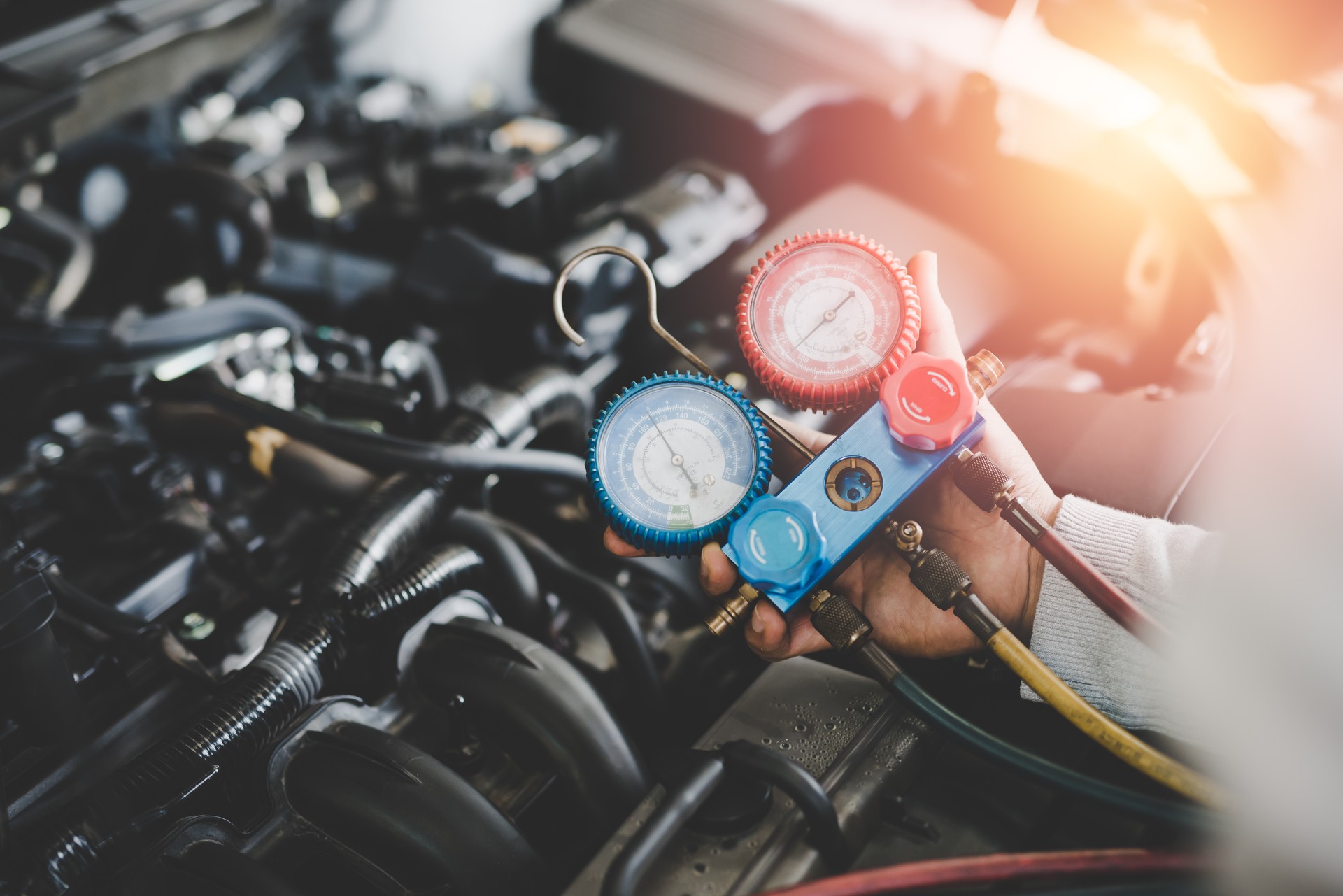 Hand of young mechanic with Gauges Set, Check the pressure and leak. Servicing car air conditioner